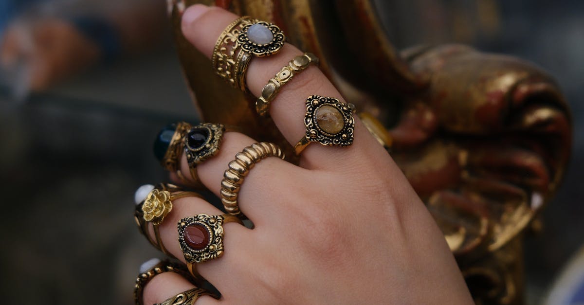 A detailed view of ornate rings on a hand holding vintage golden decor.